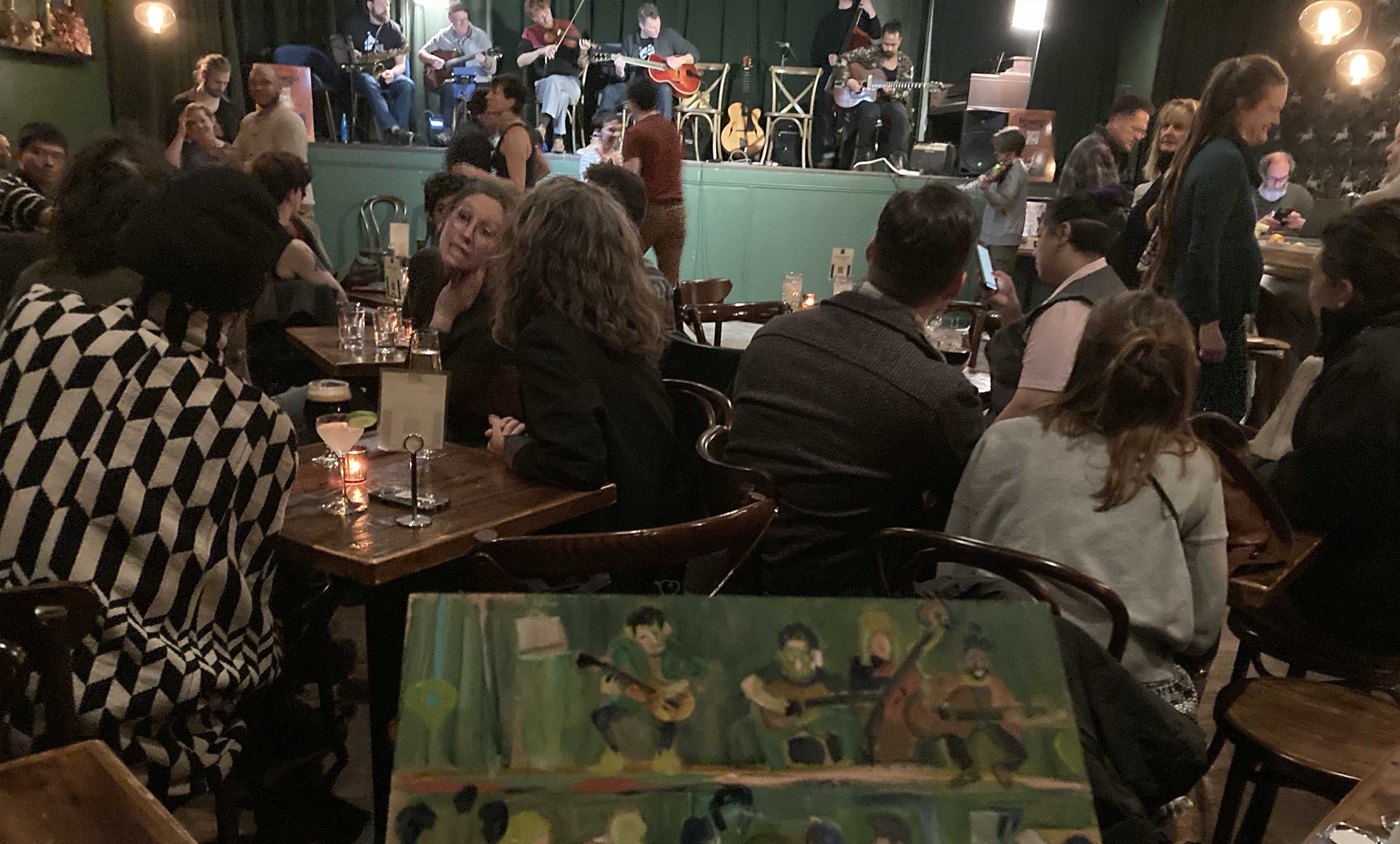 photo of inprogress painting of musicians with the musicians and audience in the background 