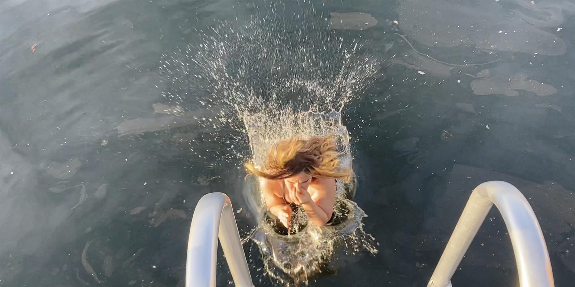 Water explodes around Jenn as she hits the harbor water